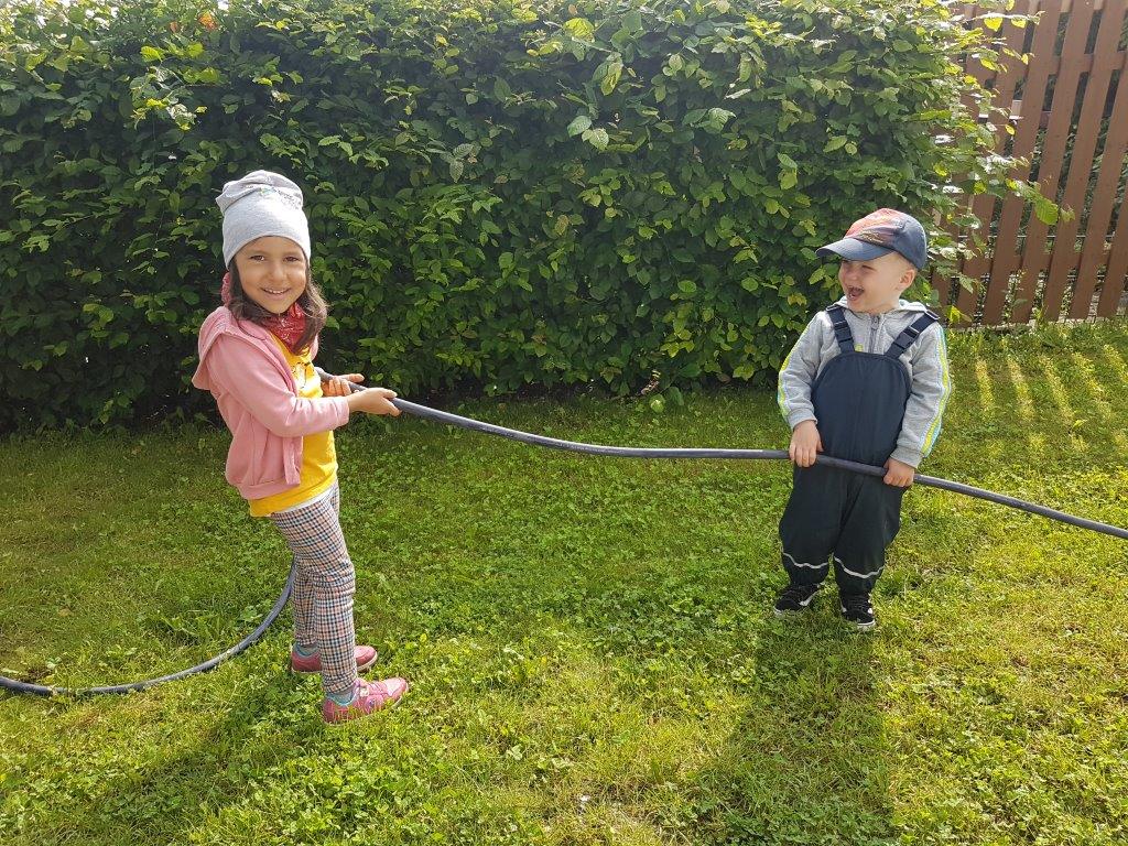 Zwei Kita-Kinder halten den Wasserschlauch für die Matschküche